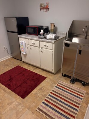 A kitchen with a refrigerator, microwave, sink, and cabinets. There are two rugs on the floor. - Cozy 1-bedroom house in superb Conyers with AC (Conyers)
