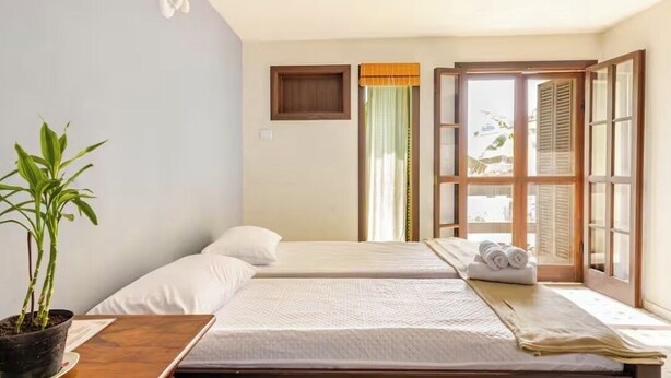A hotel room with two beds, a potted plant, and a window with shutters. - Charming loft with a mezzanine, 2 balconies, and 2 bathrooms (são sebastião)