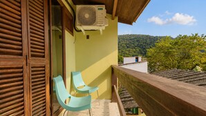 A balcony with a wooden railing, a window with wooden shutters, and a wall-mounted air conditioning unit. - Charming loft with a mezzanine, 2 balconies, and 2 bathrooms (são sebastião)