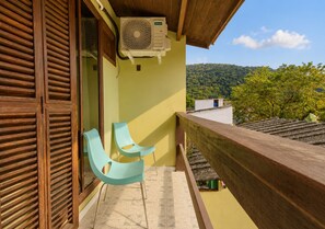 Ein Balkon mit Holzgeländer, ein Fenster mit Holzläden und eine wandmontierte Klimaanlage.