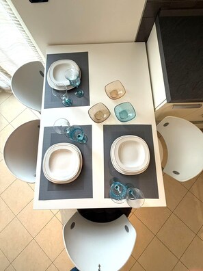 A dining table with four chairs, a white tablecloth, and a variety of glassware and plates. - Stylish Apartment in Arco, North Garda Lake – Private Garage, Balcony & A/C (Riva del Garda)