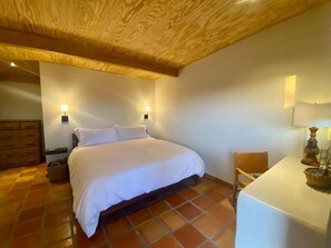 Une chambre à coucher avec un lit, une table de chevet, une chaise et une table avec une lampe.
