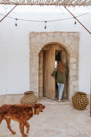A stone doorway with a wooden door, a dog, and woven baskets. - The Study Butte Entire Property (Terlingua)