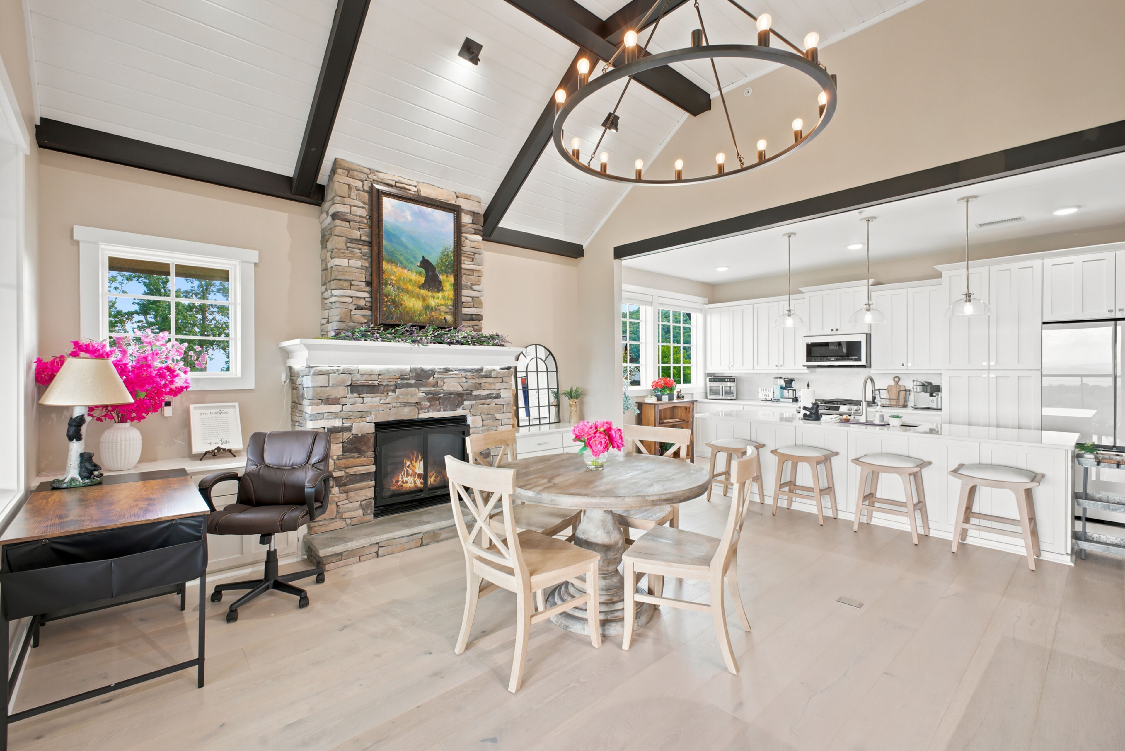A spacious living area with a fireplace, dining table, and kitchen area with white cabinets and a large island.