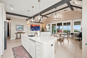 A spacious kitchen with a large island, pendant lighting, and a view to the outside.