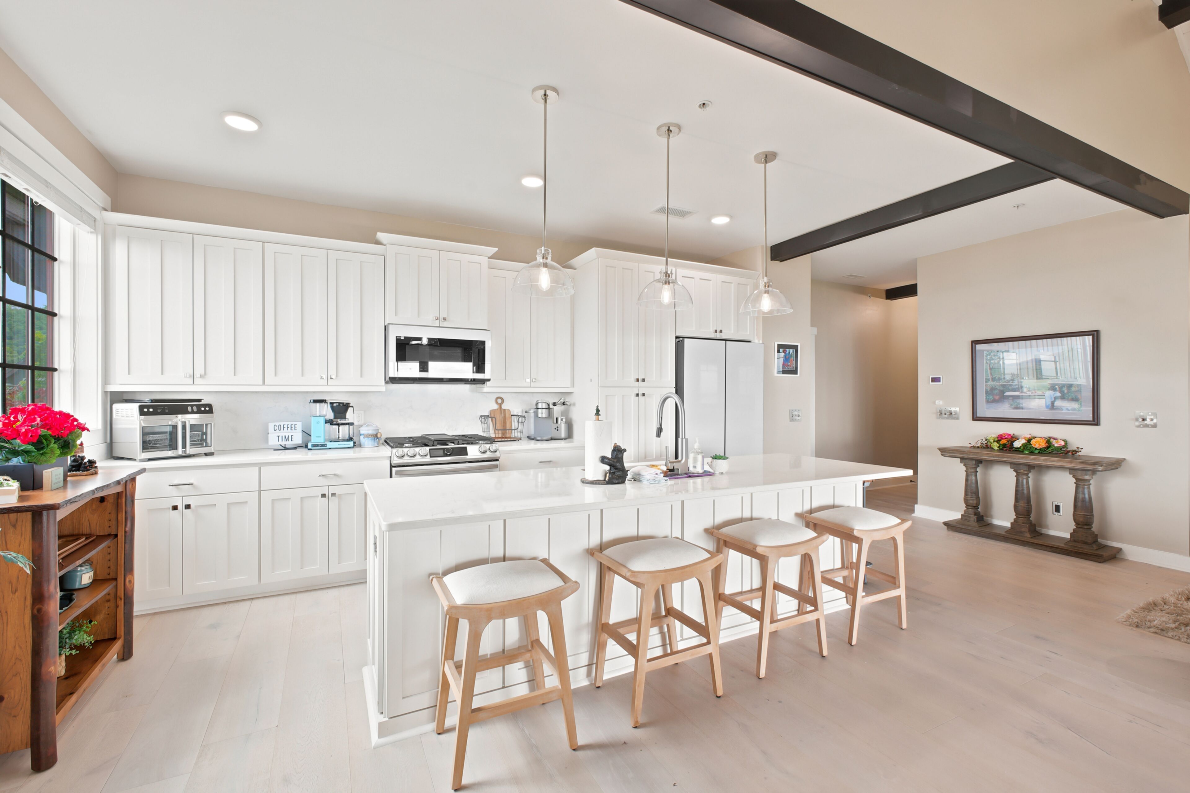 A modern kitchen with white cabinetry, a central island with bar stools, and pendant lighting.