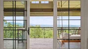 A wooden deck with a view of a mountainous landscape through a glass door with a metal grid.
