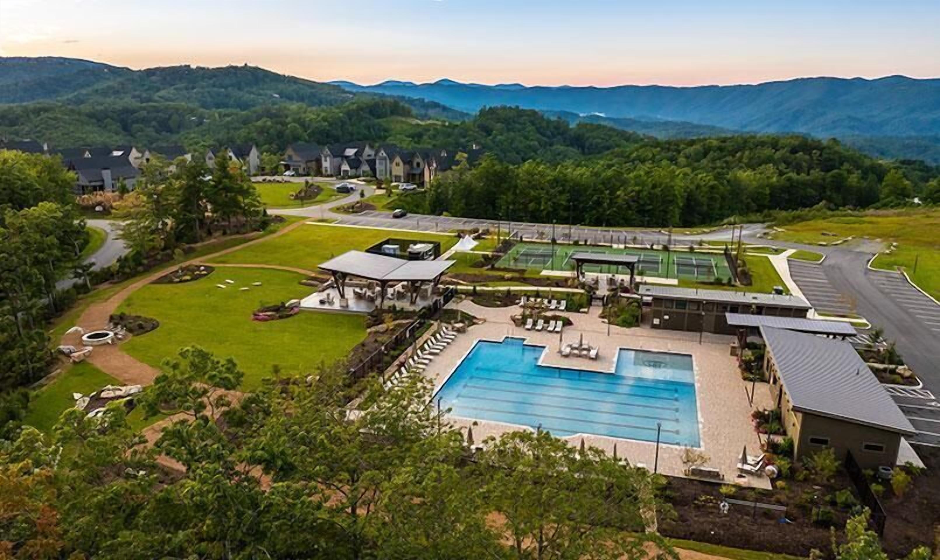 A resort with a swimming pool, tennis courts, and a covered pavilion.