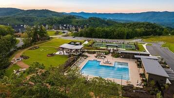 A resort with a swimming pool, tennis courts, and a covered pavilion.