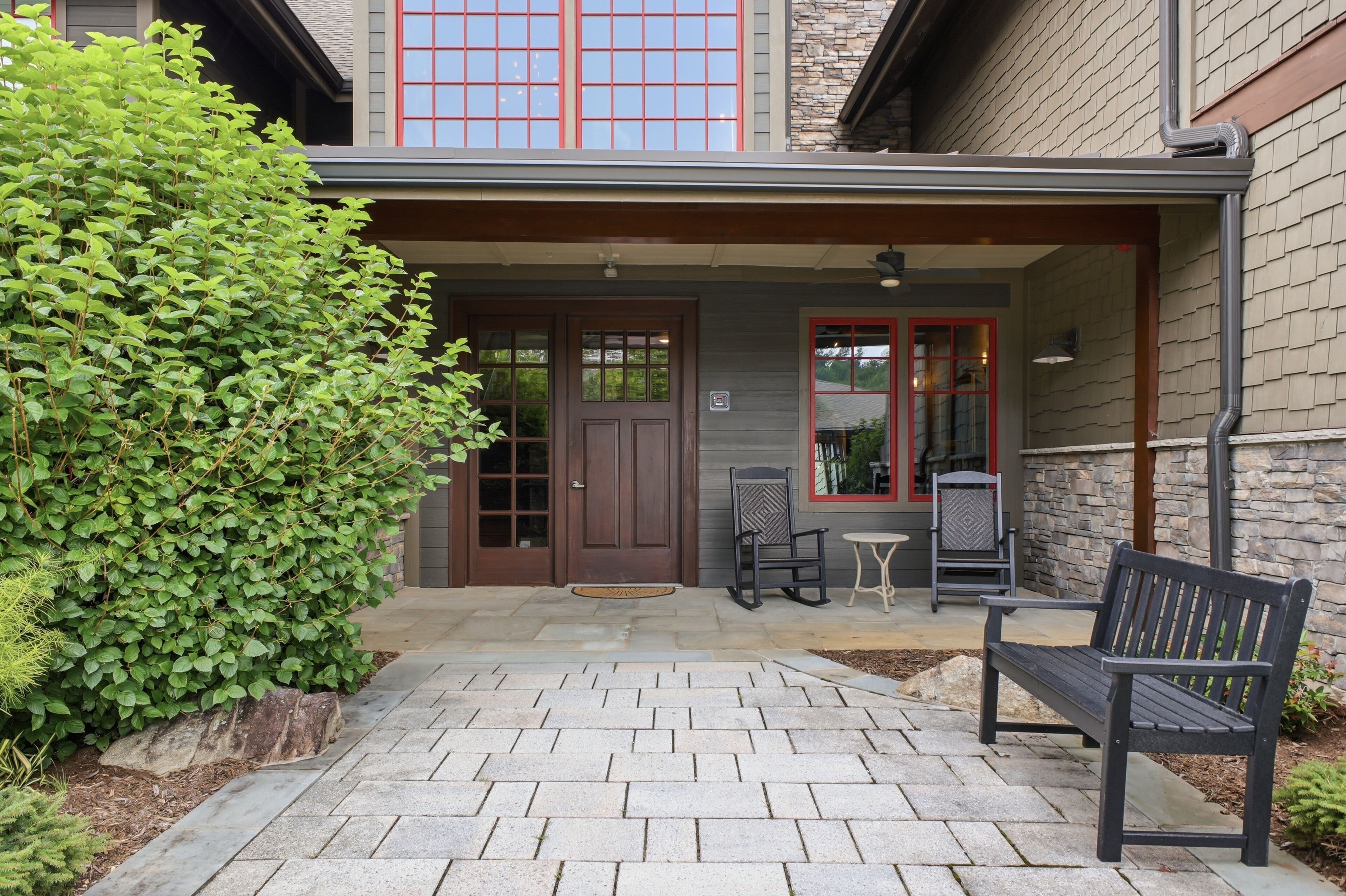 A building entrance with a covered porch, a bench, and a small table.