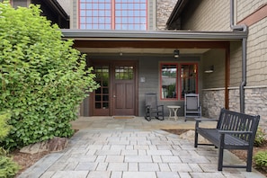 A building entrance with a covered porch, a bench, and a small table.