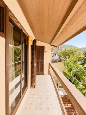 A balcony with a wooden railing, a tiled floor, and a view of greenery and hills. - Charming loft with a mezzanine, 2 balconies, and just 10 minutes from the beach (são sebastião)