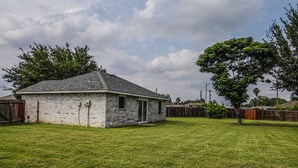 A single-story house with a brick exterior, a front door, and a small window. - Cozy Case Mena . Pet Friendly . Fiber WiFi (San Juan)