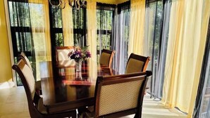A dining area with a dark wooden table, six chairs, and a vase with flowers. - LakeHouse7-bedroom house perfect for events and family fun near Sand Springs (Sand Springs)