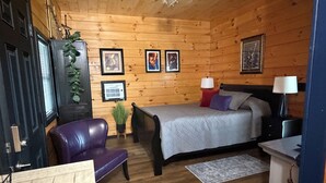 A wooden-paneled room with a bed, a desk, a chair, and a lamp. - Jazzy Moon Log Cabin Gorgeous Ozark Mountain Country View No Cleaning Fees (Eureka Springs)