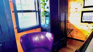 A room with a purple chair, a wooden cabinet, and a window with blinds. - Jazzy Moon Log Cabin Gorgeous Ozark Mountain Country View No Cleaning Fees (Eureka Springs)