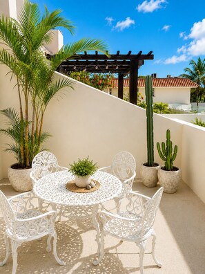 An outdoor patio with a round table and white chairs, surrounded by potted plants and a pergola. - 10 guests, amazing 3-bedroom apartment in downtown Playa del Carmen (Playa del Carmen)