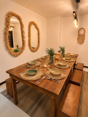 A dining room with a long wooden table set for a meal, two wall mirrors with fringe, and a hanging light fixture. - 10 guests, amazing 3-bedroom apartment in downtown Playa del Carmen (Playa del Carmen)