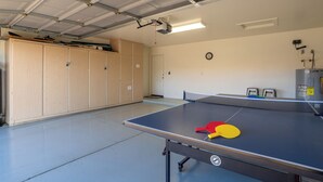 A ping pong table with paddles, a clock, and a heater in a room with wooden cabinets and a door. - *Scottsdale Kierland*Pool*Spa*Water Fall* (Scottsdale)