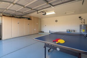 A ping pong table with paddles, a clock, and a heater in a room with wooden cabinets and a door. - *Scottsdale Kierland*Pool*Spa*Water Fall* (Scottsdale)