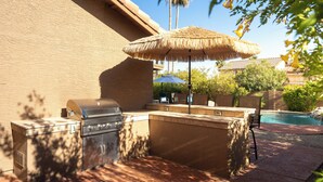 An outdoor kitchen area with a grill, a built-in sink, and a seating area with a table and chairs. - *Scottsdale Kierland*Pool*Spa*Water Fall* (Scottsdale)