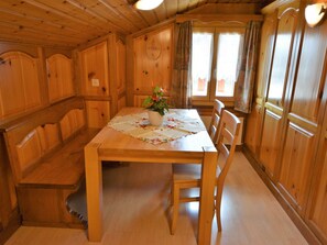 Ein Esszimmer mit Holzboden, Tisch für vier Personen, einer Bank und einem Topf mit Pflanze.