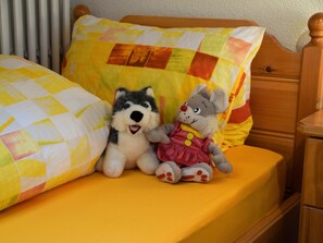 Ein Bett mit einem gesteppten Kopfkissen und zwei Stofftieren.