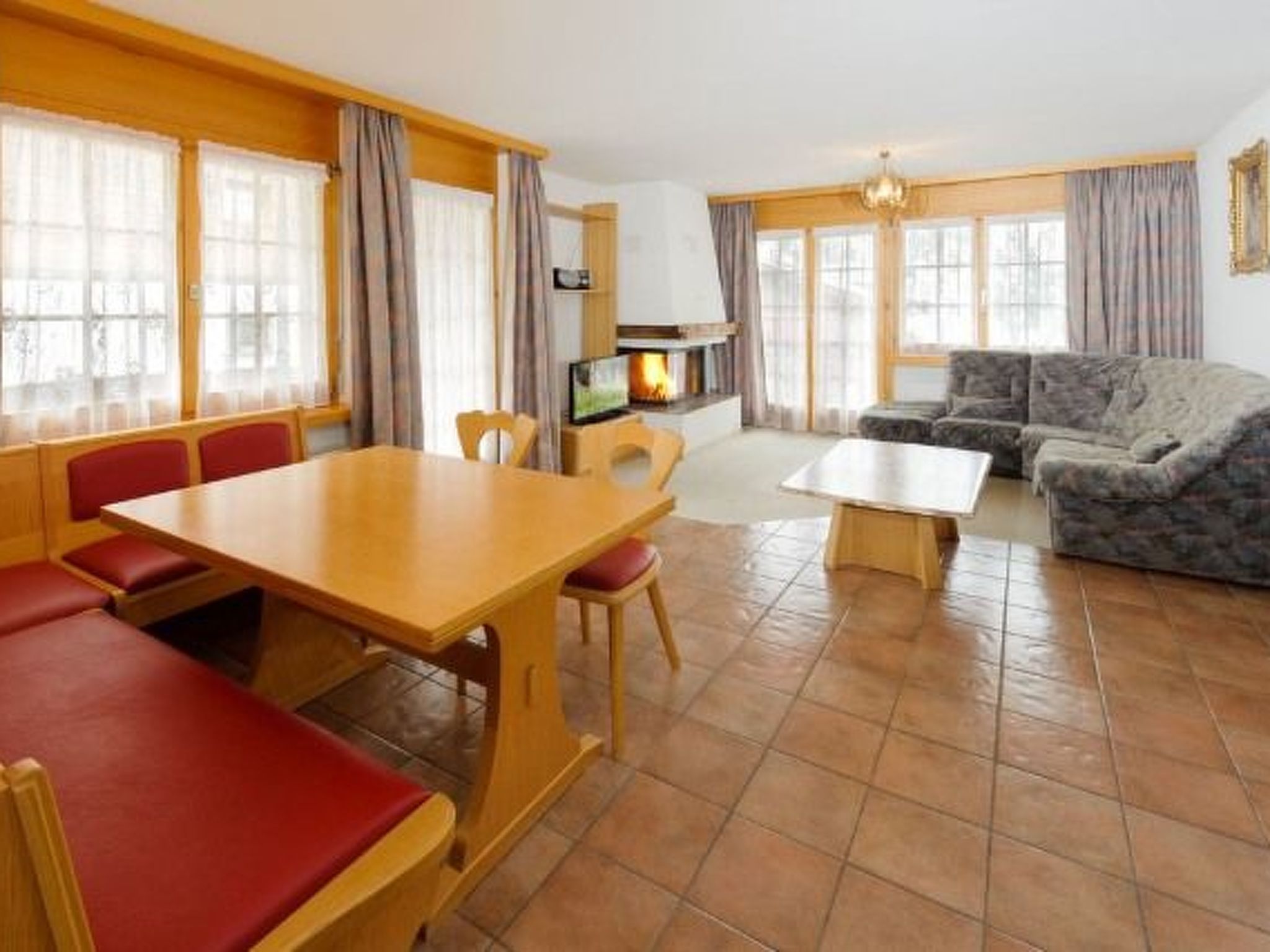 A room with a dining table, chairs, a sofa, and a television.