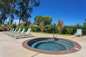 A swimming pool with lounge chairs, surrounded by trees and a clear sky. - Sunset, Ocean, and Golf Course Views! (Waikoloa Village)