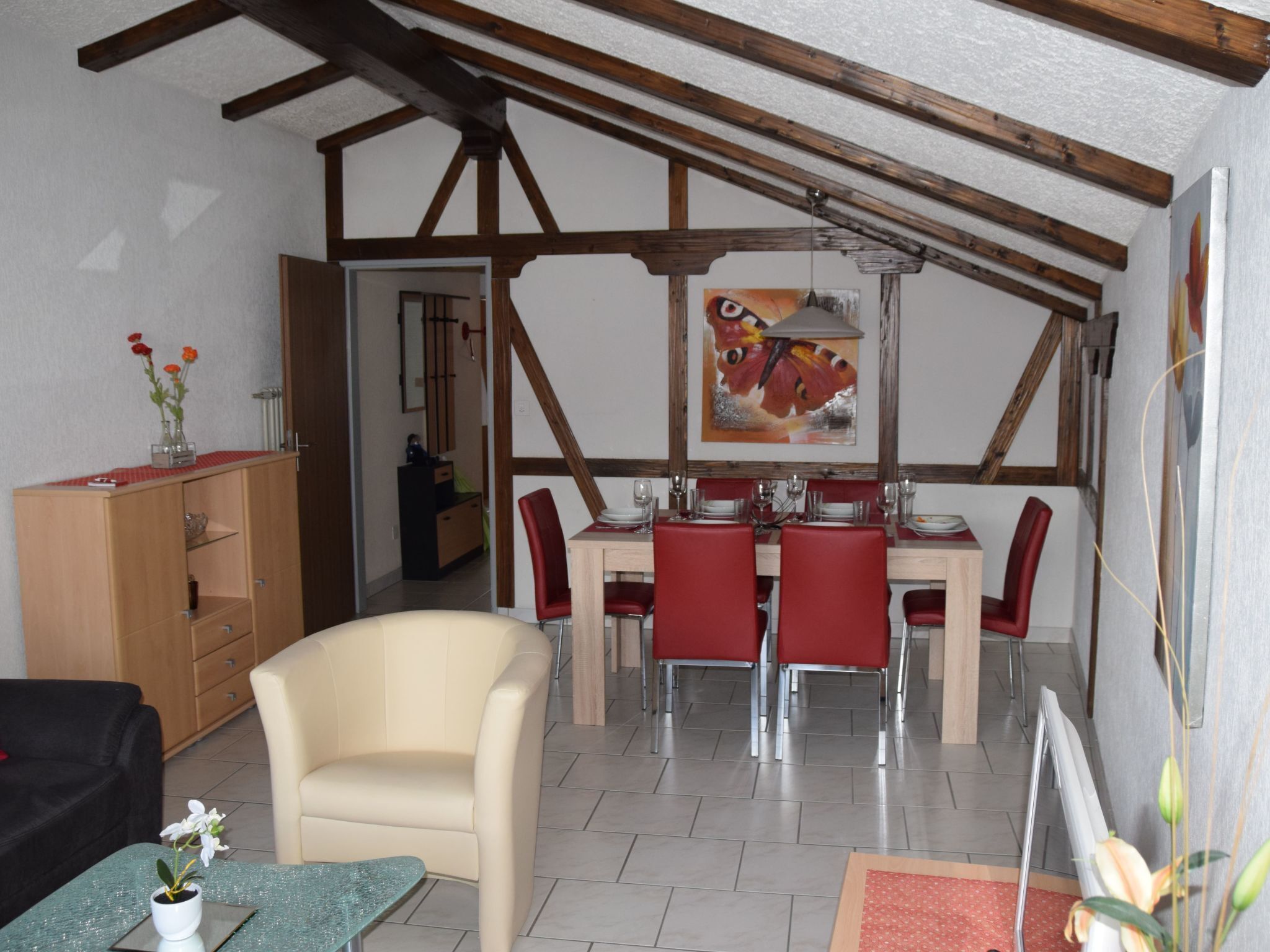 A dining area with a wooden ceiling, red chairs, and a table set for four.