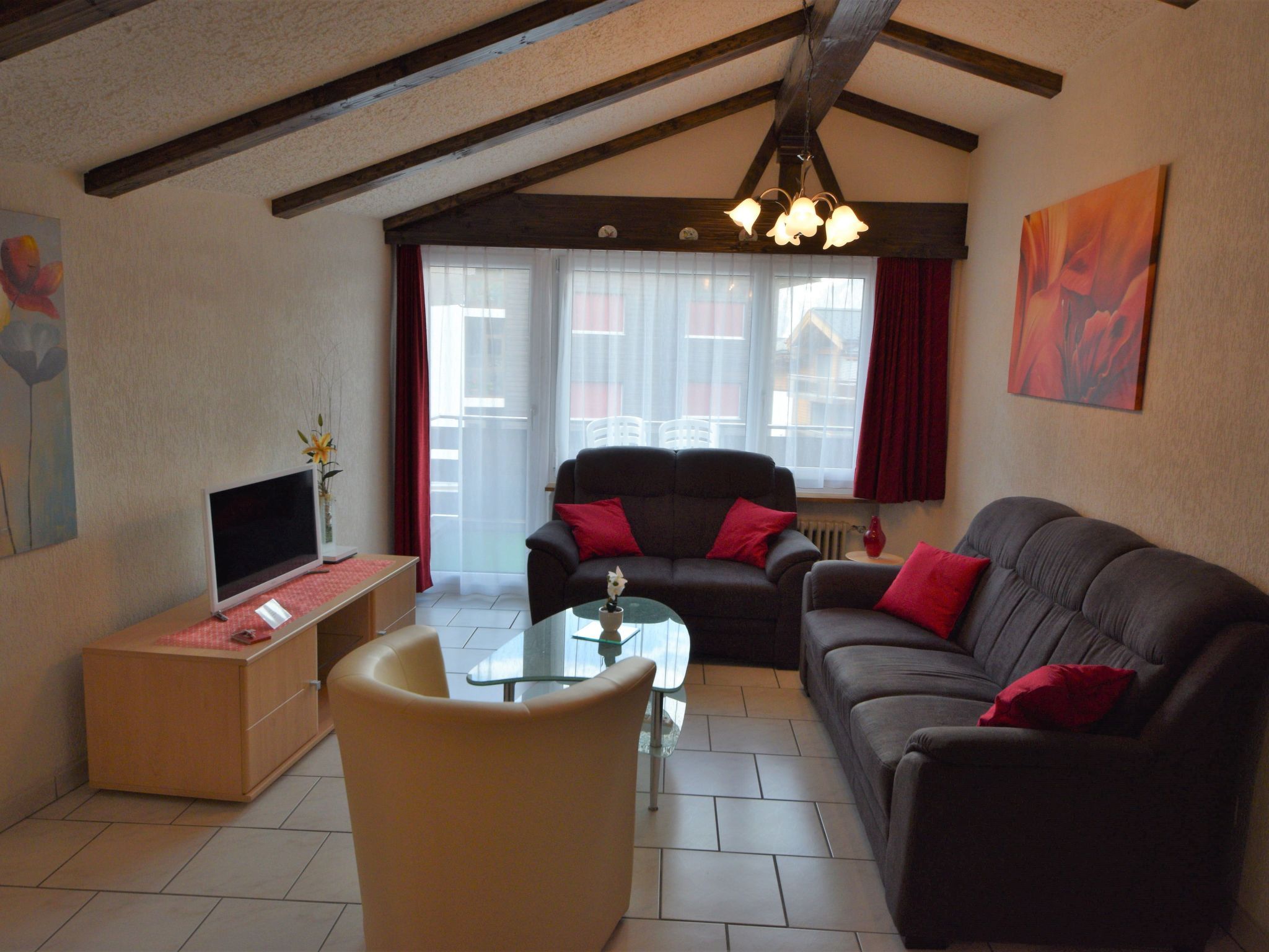 A furnished living room with a sofa, armchair, coffee table, and a television on a wooden cabinet.