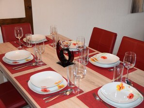 A dining table set with plates, glasses, and cutlery, surrounded by red chairs. - Brunegghorn Biner, (Grächen), 1104 by Interhome (Grächen)