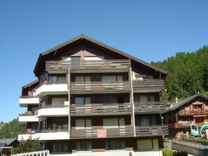 A multi-story building with balconies, likely a hotel or apartment complex, surrounded by greenery. - Brunegghorn Biner, (Grächen), 1104 by Interhome (Grächen)