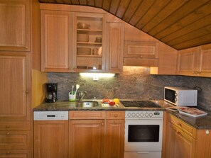 Eine Küche mit Holzausstattung, einem Herd, einer Mikrowelle und einem Spülbecken.