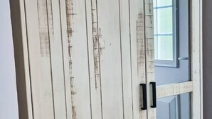 Una porta bianca con assi verticali e maniglie nere.