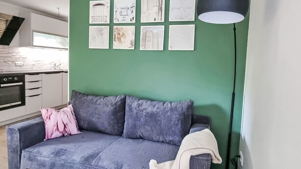 Un soggiorno con una parete verde, un divano, un tavolino da caffè e una lampada da terra.