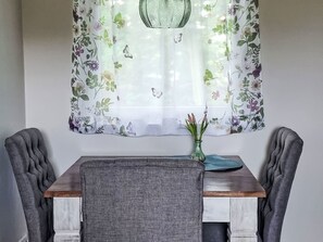 A dining area with a table, chairs, and a floral curtain. - Gästehaus am Neetzekanal by Interhome (Bardowick)
