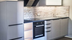 Una cucina con forno a incasso, piano cottura e pannelli di pietra a rivestimento.