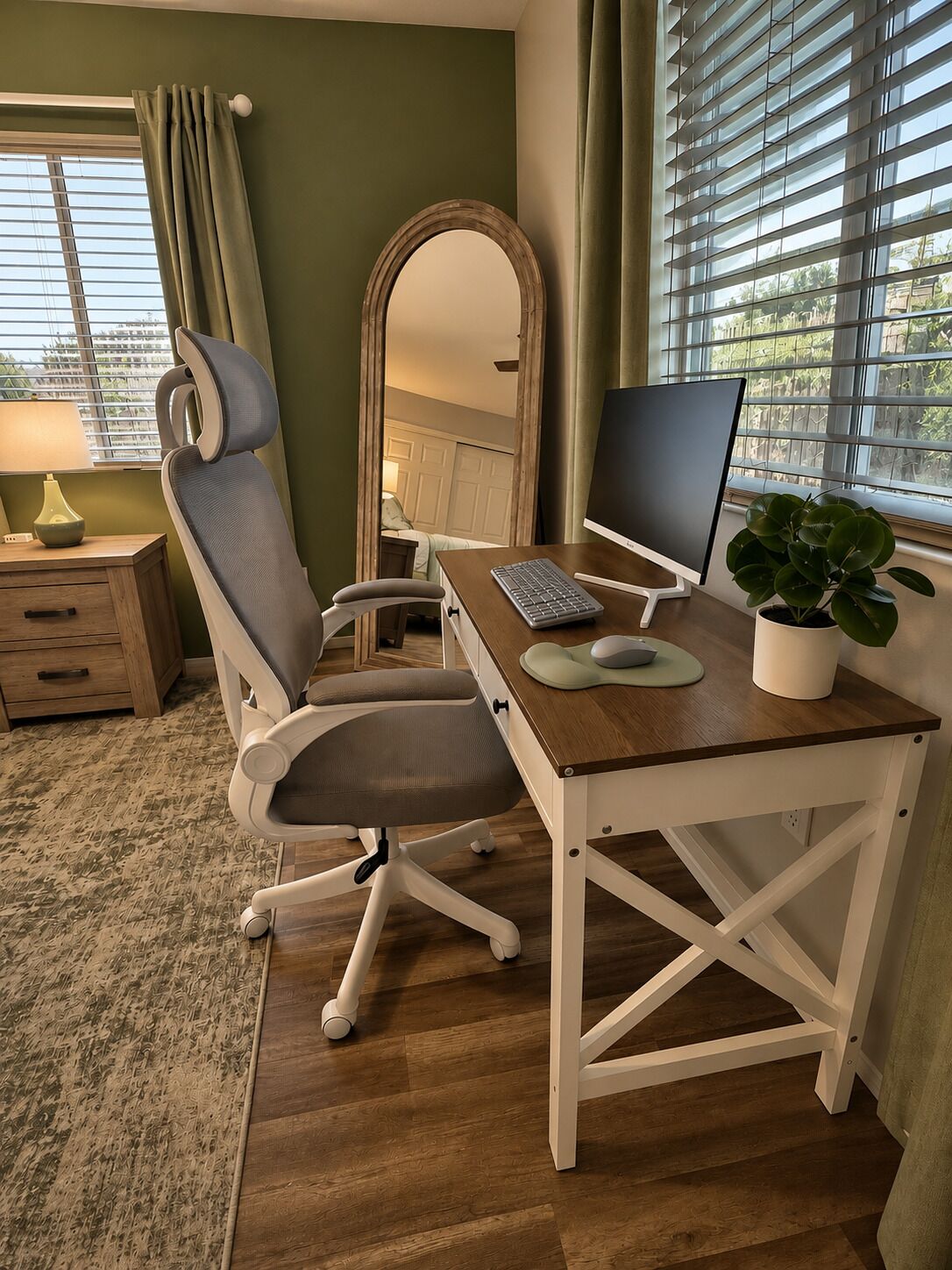A room with a desk, chair, computer, and a potted plant.