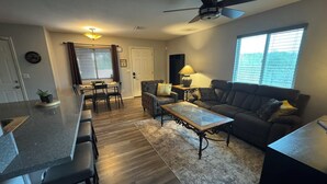 A modern living room with a sofa, coffee table, and dining area. - Route 66 River House: 8 Min to Boat Launch, Boat & Trailer Parking (Mohave Valley)