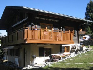 Ein zweistöckiges Gebäude mit Balkon, einer Veranda und einem geparkten Auto davor.