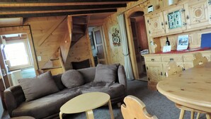 A wooden interior with a sofa, a round table, and a wooden cabinet. - Föhre, (Grächen), 1420 by Interhome (Grächen)