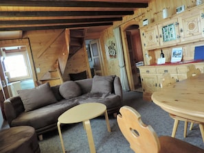 Ein Holzinterieur mit einer Couch, einem runden Tisch und einem Holzschrank.