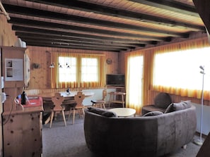 Ein gemütliches Wohnzimmer mit einer Couch, einem Fernseher und Holzwänden.
