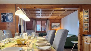 Et spiseområde med et træbord dækket til måltid, en sofa og et skab.