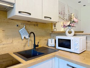 A modern kitchen with a sink, a toaster, a microwave, and a vase with flowers on the counter. - Des Kaisers kleines Reich by Interhome (Kitzbühel)