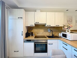 Eine kompakte Küche mit weißen Schränken, einem Backofen, einer Mikrowelle und einer Kaffeemaschine.