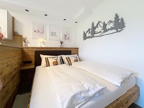A bedroom with a bed, wooden headboard, and a wall-mounted decoration. - Des Kaisers kleines Reich by Interhome (Kitzbühel)