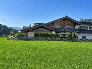 A two-story chalet with a sloped roof, wooden exterior, and a balcony with purple flowers. - Des Kaisers kleines Reich by Interhome (Kitzbühel)