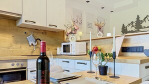 Une cuisine moderne avec un plan de travail en bois, une bouteille de vin, un four à micro-ondes et un coin repas avec une table mise pour deux personnes.
